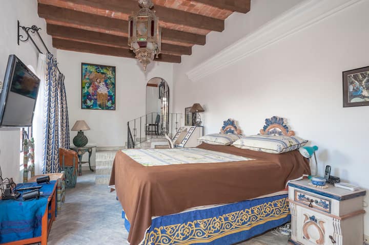 Dormitorio Blue Suite con arte original y muebles pintados a mano y TV de alta definición.