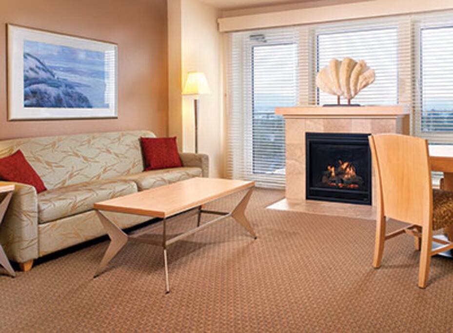 Living room with gas fireplace, balcony and queen Murphy bed.