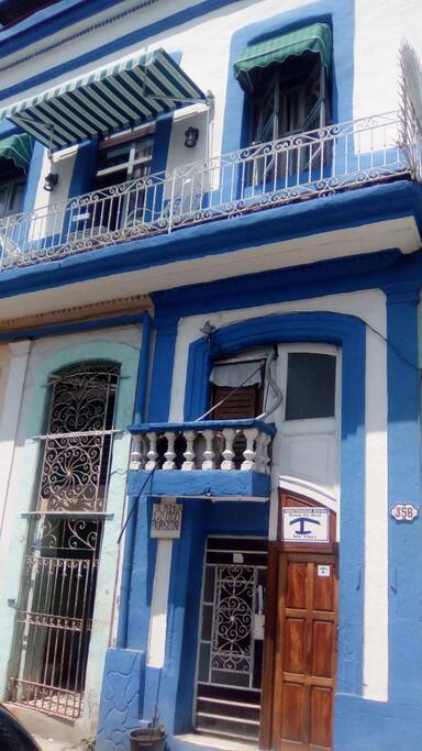Fachada de la casa, estilo colonial, en la planta baja se accede a la escalera y la casa está en el primer piso,el cuarto de este anuncio posee balcón, con sillas y mesita. En el segundo piso terraza techada con excelente vista de la zona antigua de la ciudad.