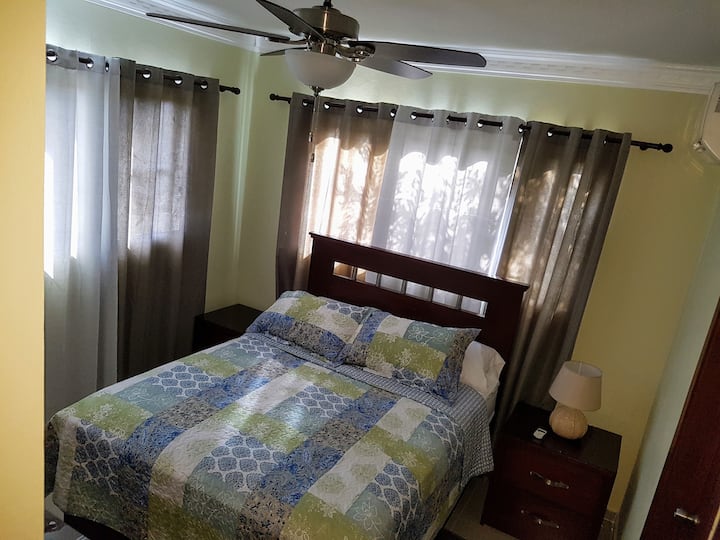 Habitación Principal. Dispone de baño privado, w.c., aire acondicionado, abanico de techo, un Smart Tv y gavetero con espejo.