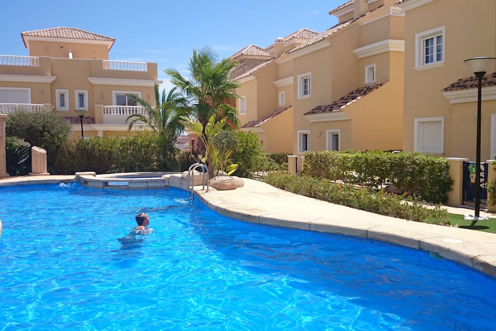 The spacious common pool in a beautifull garden with palmtrees and other plants