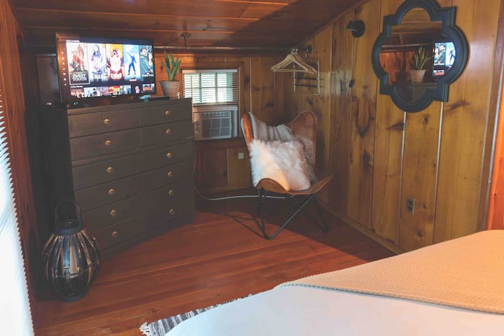 חדר שינה אחורי עם מיטת קווין סייז , טלוויזיה, שידה, שידת לילה, אורות קיר, כיסא קריאה וארון 