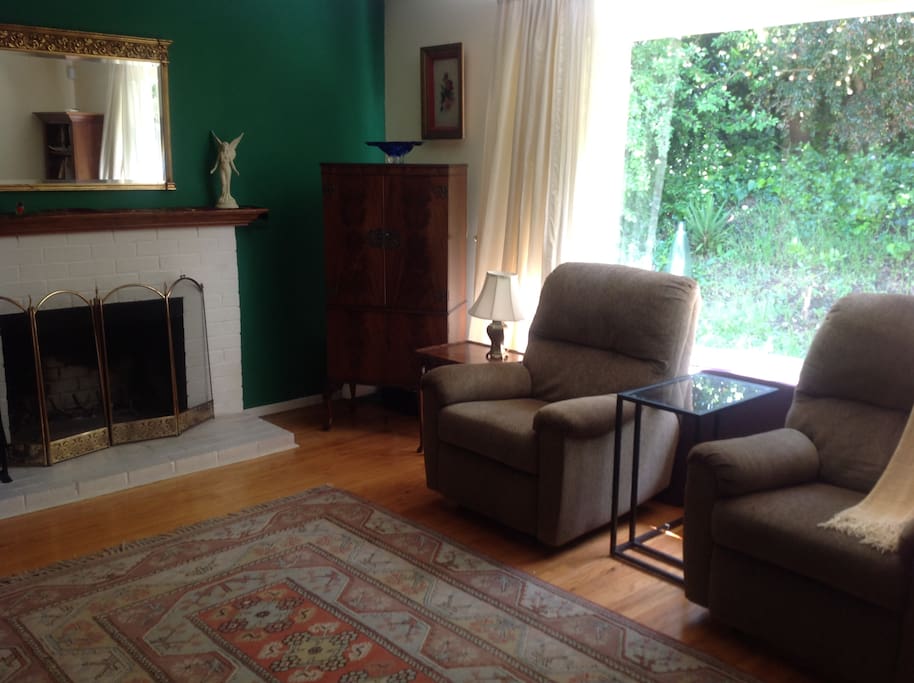 Comfortable living room with fireplace in good working order and picture window to the luscious garden.