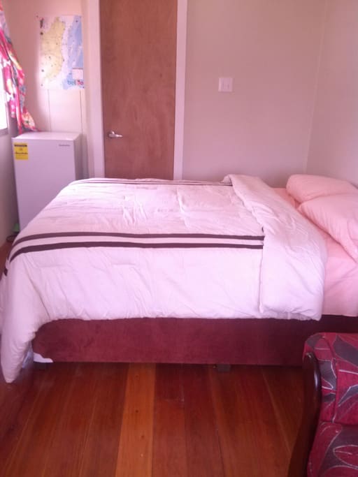 Double bed, refrigerator, and entrance to the private bathroom.