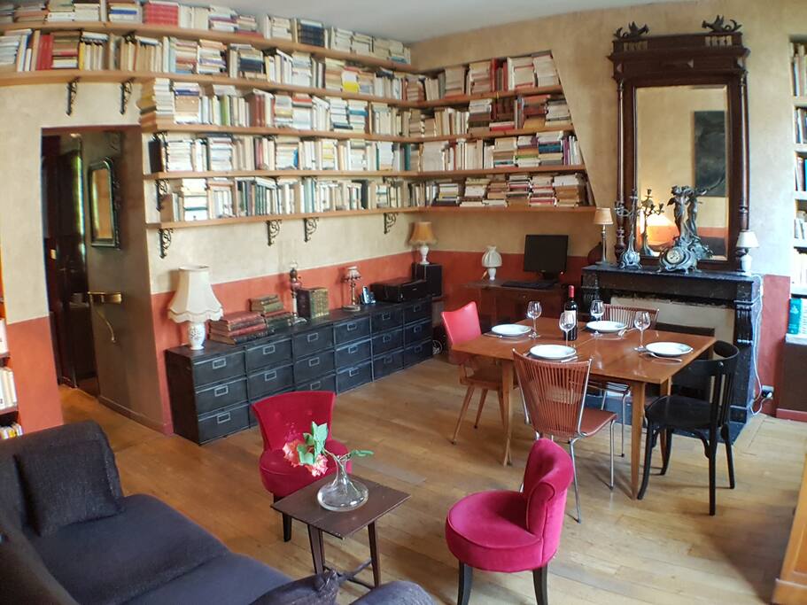Le séjour vue vers l'entrée. La table est ouverte, dépliée. Nous sommes passionnés de littérature. Marie est artiste peintre. The living room view towards the entrance. The table is open, unfolded. We are passionate about literature. Marie is a painter.