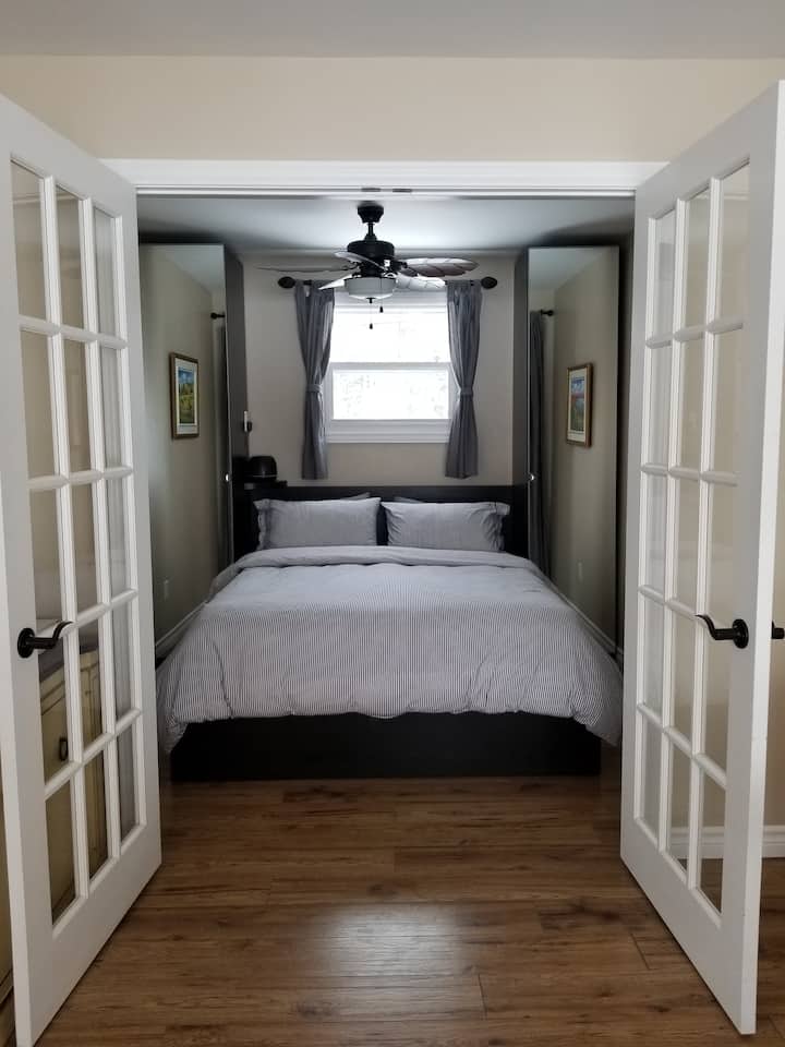 Bedroom with a queen size bed located on the main level/ Chambre avec lit queen située au niveau principal.