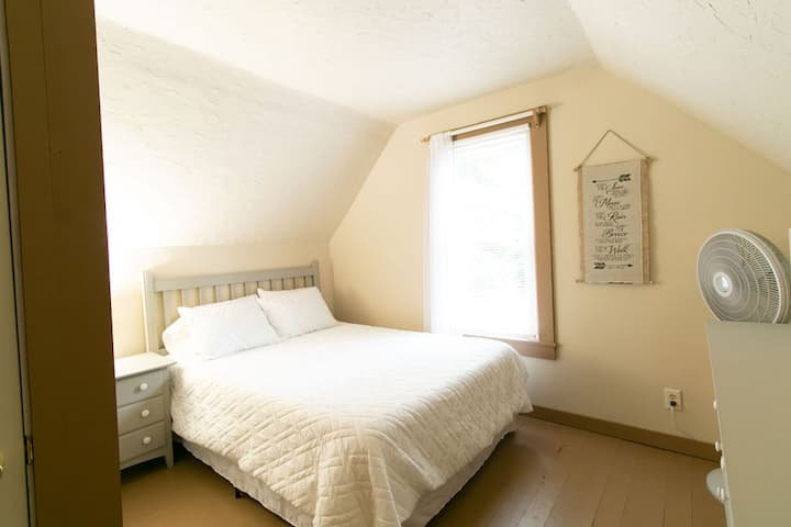 Master bedroom with comfy queen bed, crisp white linens, dresser, night stand, closet and pedestal fan for your comfort.