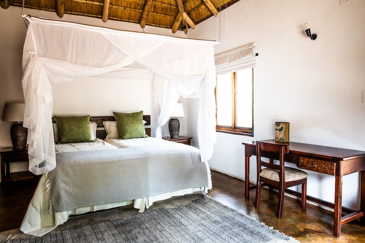 Chambre n °2 avec lit King Size, coin salon, armoire, bureau et salle de bain attenante avec douche.