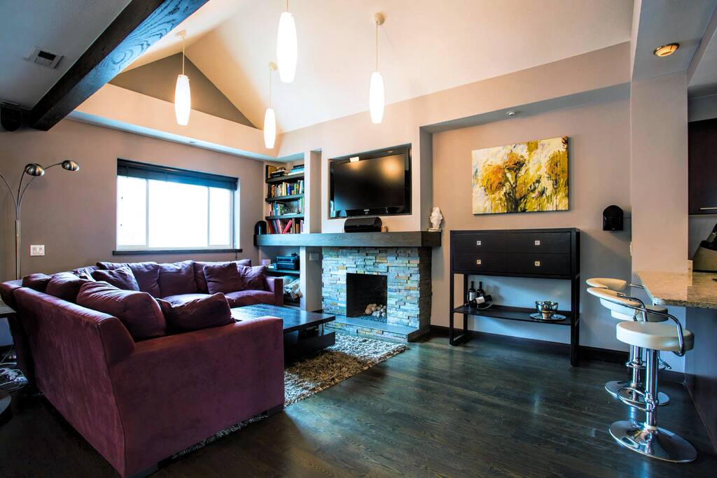 Stonework gas fireplace, 52 inch adjustable, flat screen tv and 14-foot Crate and Barrel suede couch.