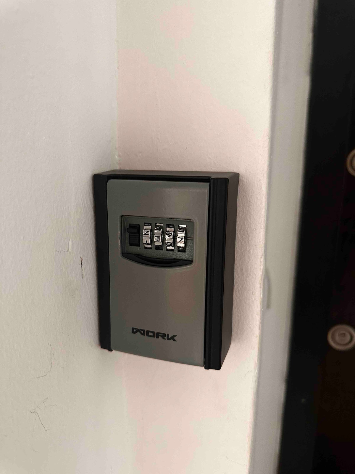 A secure wall-mounted lockbox is visible, featuring a numerical keypad. The device is positioned on a light-colored wall, providing a practical entry solution for guests during their stay.