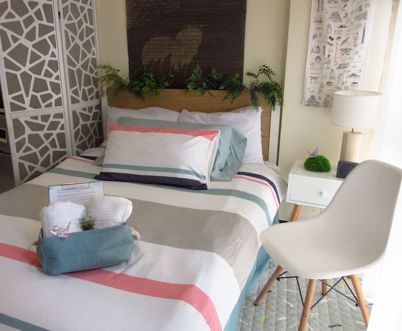 Cozy bed with the essentials and bluetooth speakers on the side table