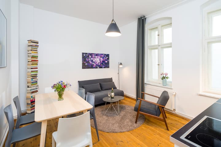 Кухня с всекидневна, маса за хранене, рафт за книги и допълнителен диван 