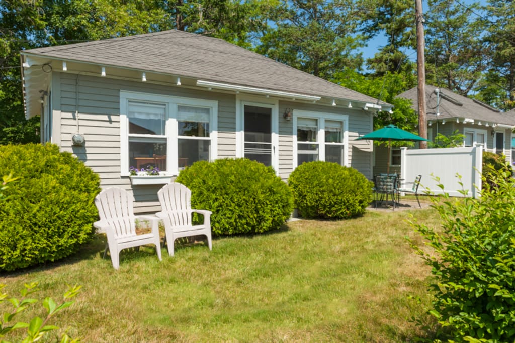 Exterior of the cottage includes adirondack chairs and a patio set