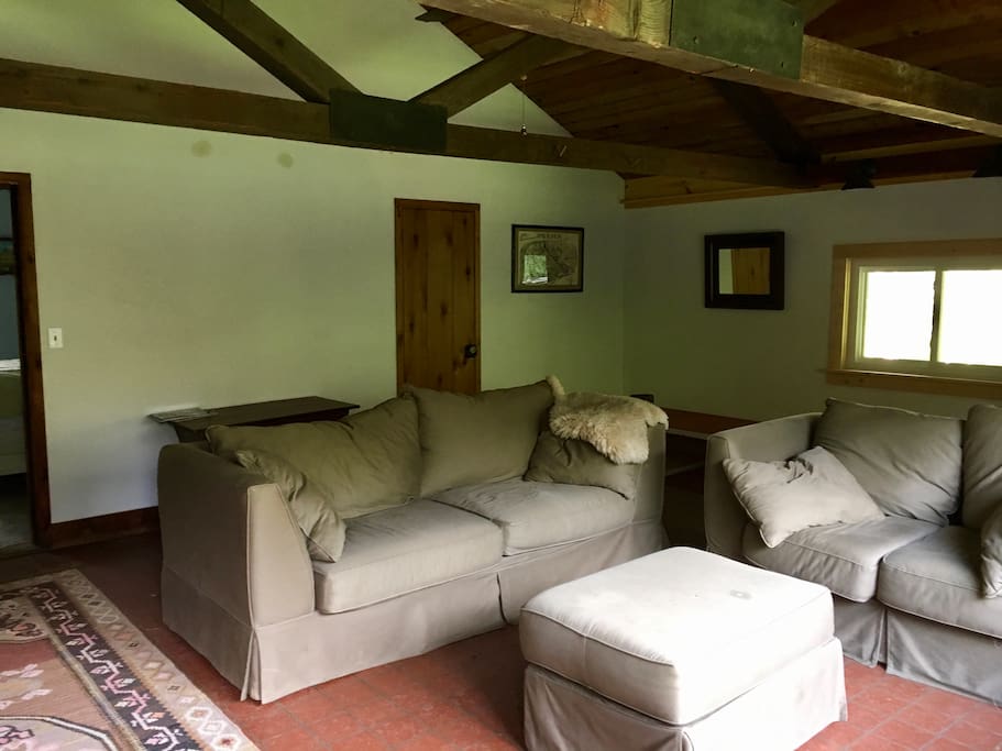 Living room with couch and love seat. This room has space for an air mattress if extra room needed. There is an open staircase in the back that leads to the downstairs.