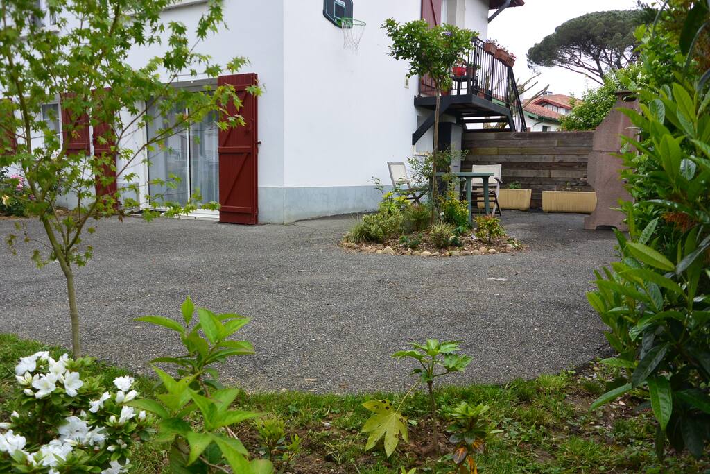 Vue extérieur du studio avec une place de parking et un coin repas extérieur avec barbecue