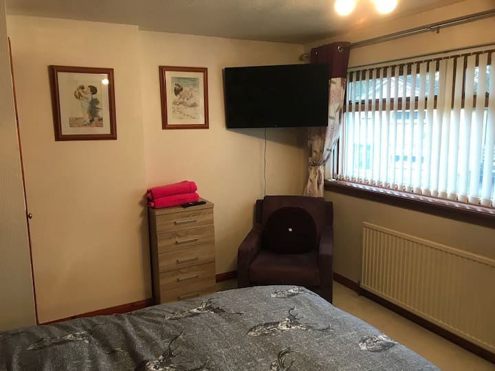 Upstairs front bedroom with built in wardrobe and 40” smart tv and nice comfy chair for relaxing on 