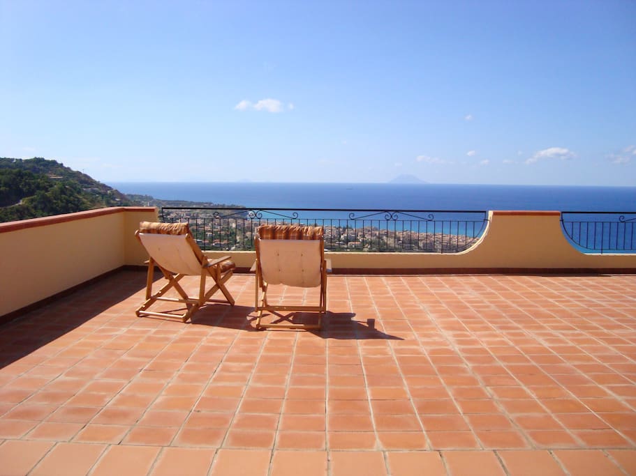 Panoramic ocean view over Tropea from sunloungers on terrace