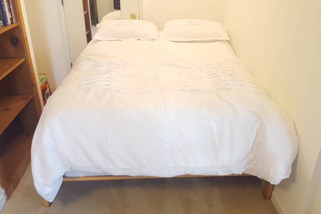 Queen bed close up, closet and bookshelf by the bed