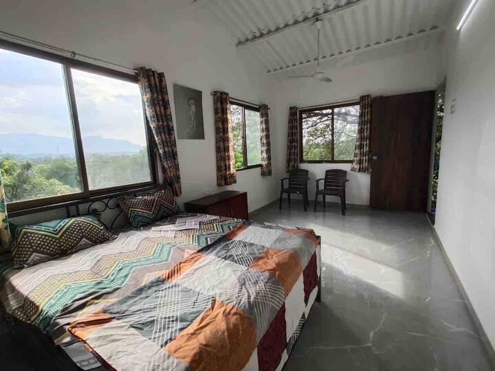 Bedroom on second floor overlooking the tree tops and mountains beyond, Room is with a double bed, AC & en-suite toilet. This is the only room that has a balcony with sit-out space.