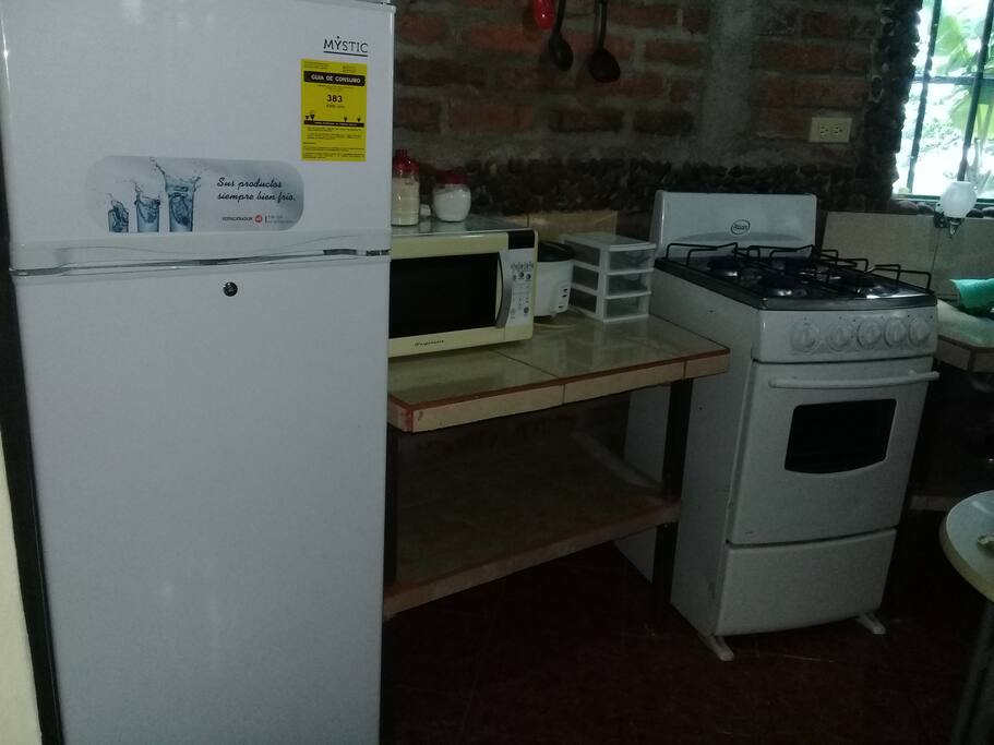 fridge kitchen stove and kitchen utencils on the kit hen area.