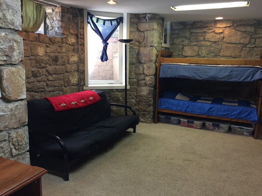 Futon and bunk bed in basement main room, extra bedding in bins under bunk bed