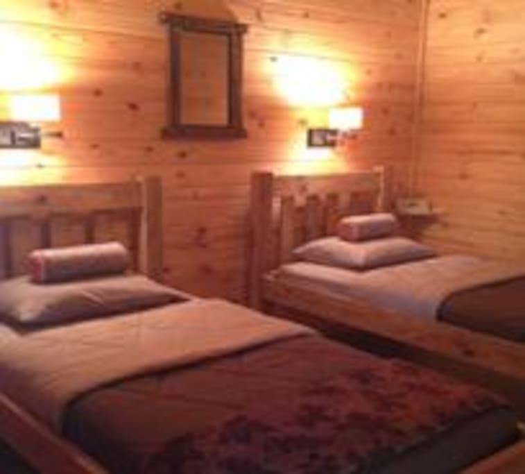 Quaint two beds in each private lodge cabin room made of oak.