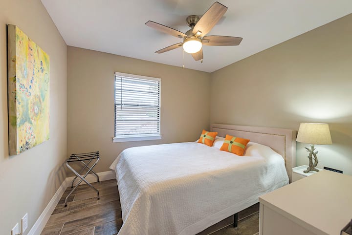 Guest bedroom with wood look tile flooring, queen bed and ceiling fan with light