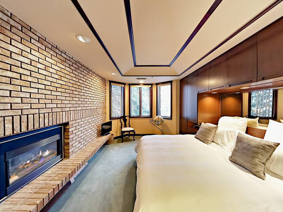 The grand master suite boasts a California king-size bed and an impressive brick wall with a gas fireplace.
