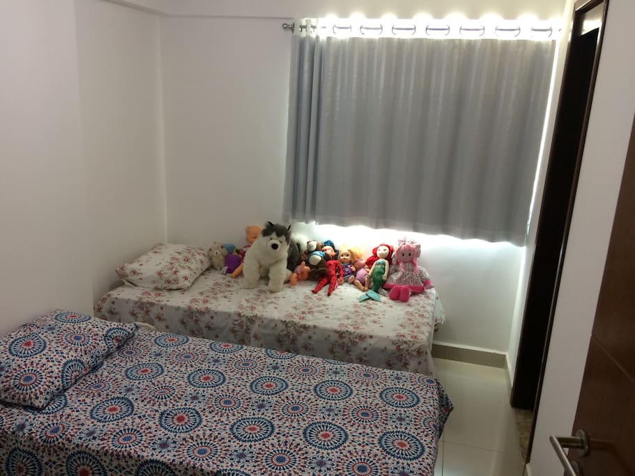 Quarto com 2 camas de solteiro, guarda roupas, ventilador e banheiro privativo reversível.