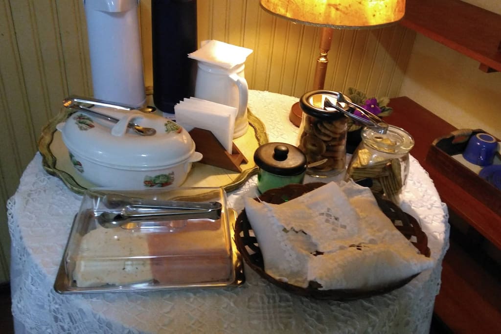 Café da manhã com queijo, presunto, leite, pães, café preto e biscoitos.