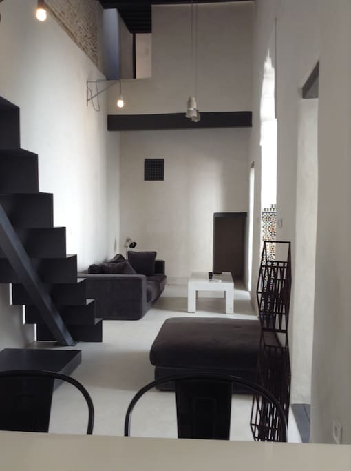 Salon avec escalier qui monte à la pièce TV