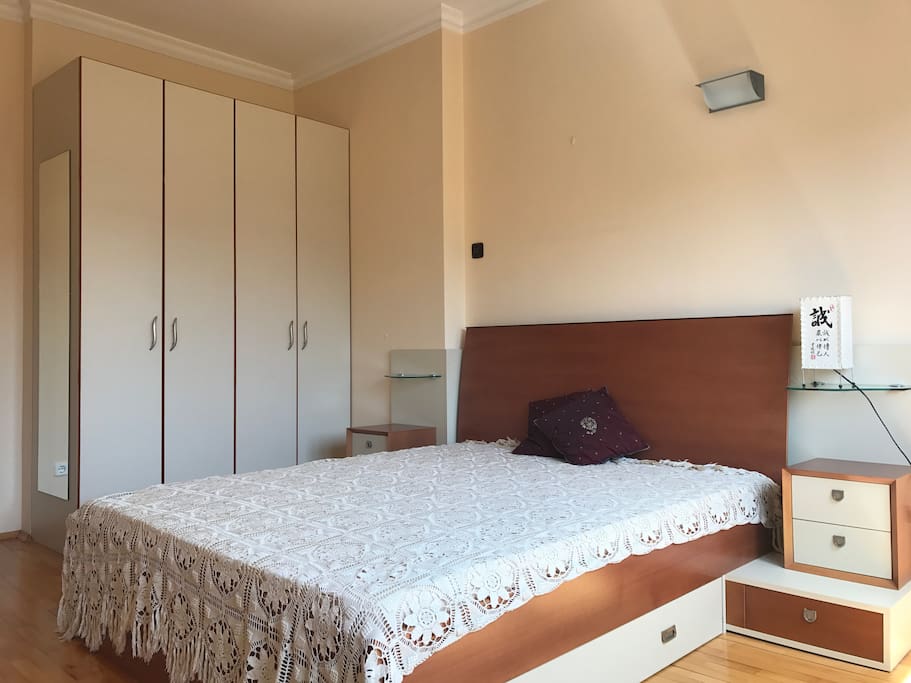 The bedroom. There is a reading lamp and two night stands.