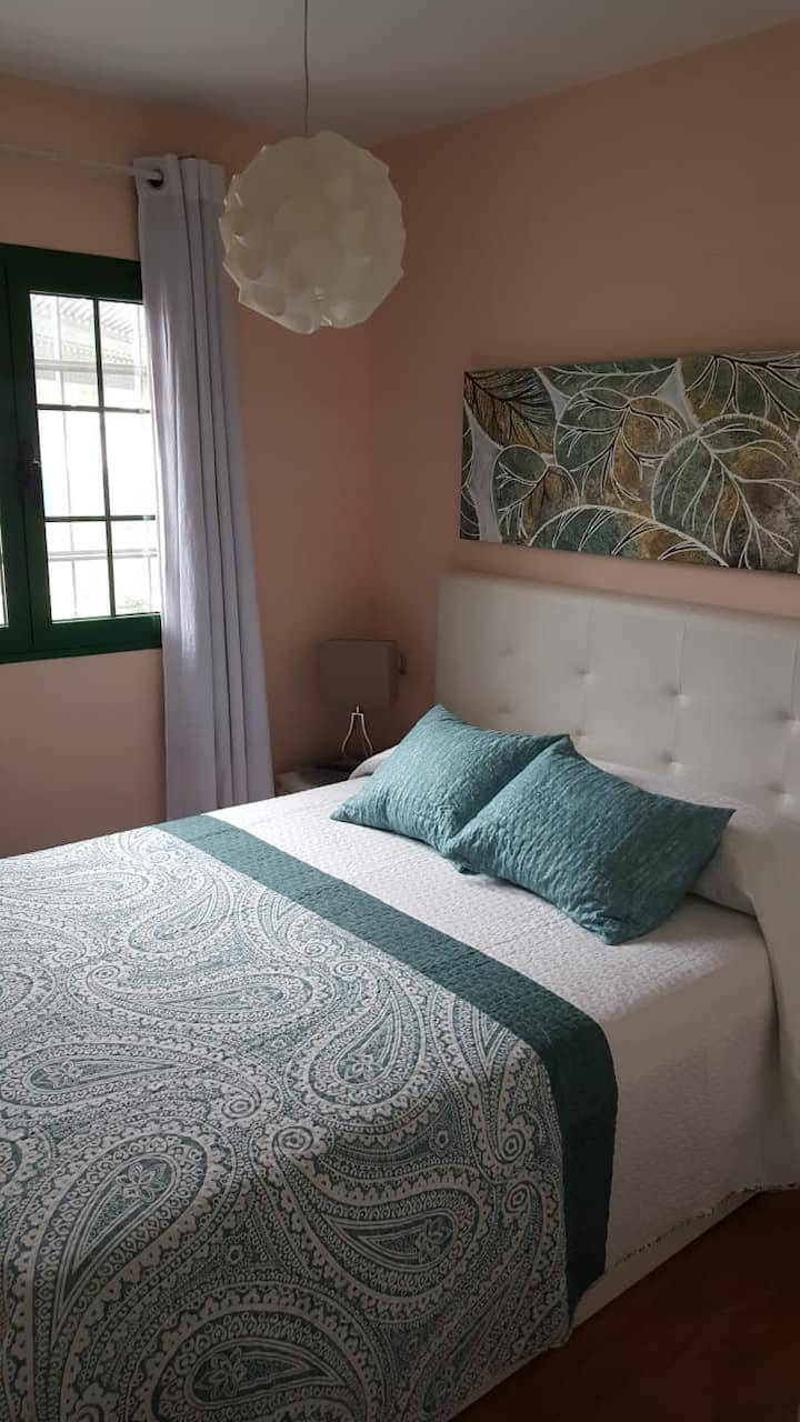 Værelse med tv, garderobe og vindue til den private terrasse med pool