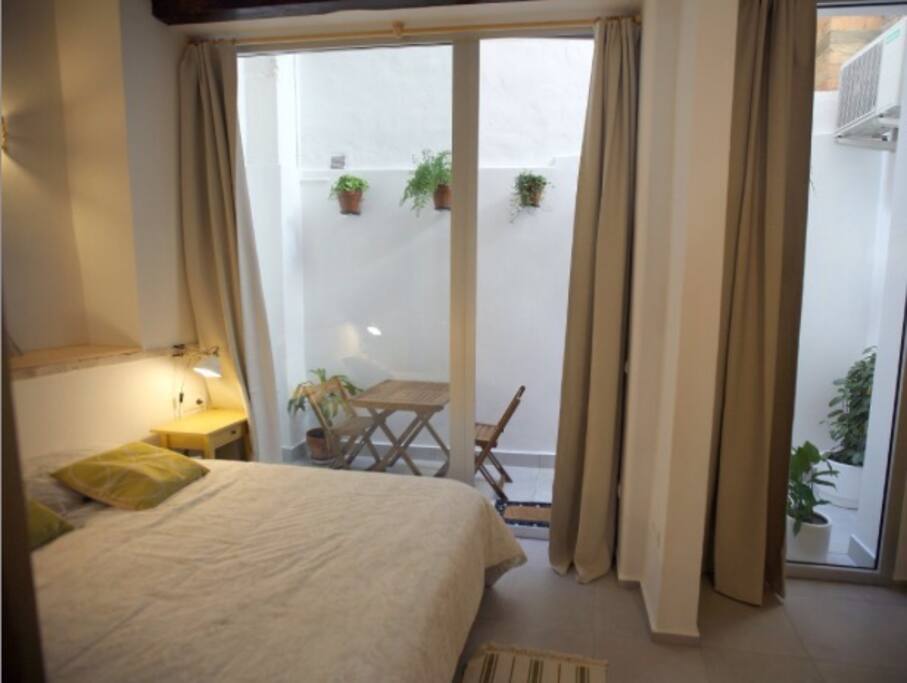 Vista desde la puerta del dormitorio hacia el patio con la iluminación de las 2 lámparas del cabecero cama.