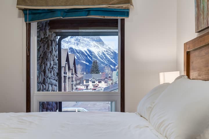 Hoofdslaapkamer met comfortabel queensize bed en uitzicht op de bergen