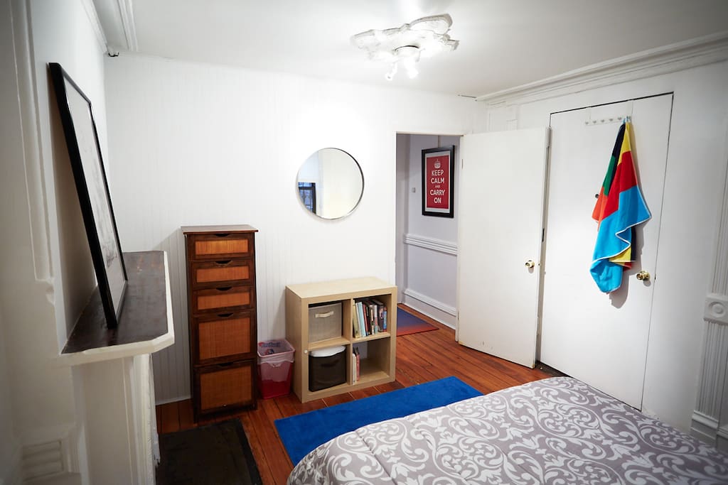 Bedroom with dresser. Spare sheets and comforter in cubes.