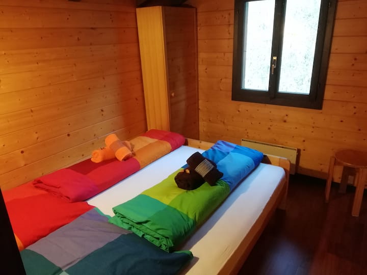 Dormitorio con cama francesa grande (160x190 cm), taburete, armario pequeño y cajones de cama.