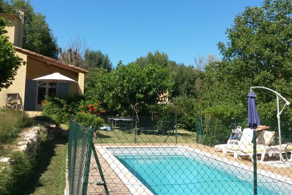 Piscine avec plage en bois, équipée de chaises longues et un parasol