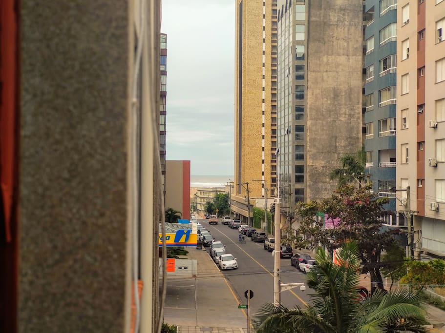 (Quarto) Vista lateral da janela. Ao fundo é possível ver a praia conhecida como Praia Grande