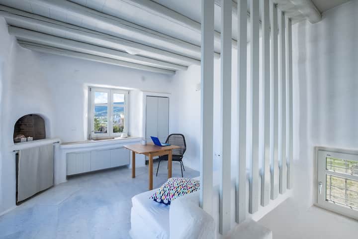 غرفة نوم مفتوحة بسرير واحد ومساحة عمل وثلاجة صغيرة