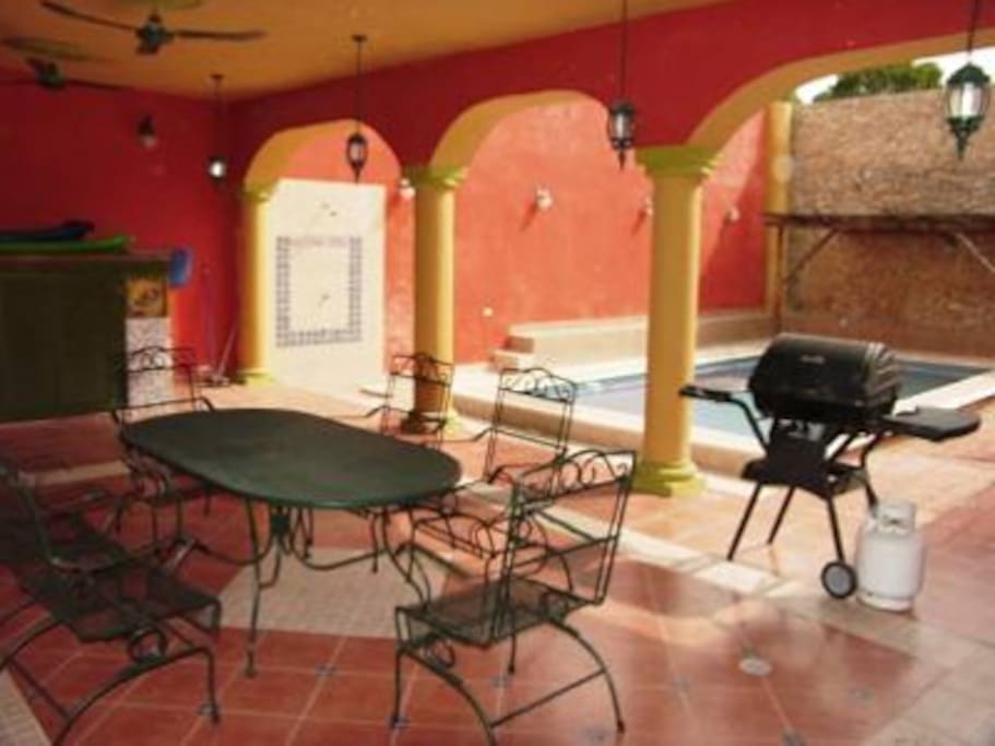 Covered patio by pool area with grill and outdoor shower