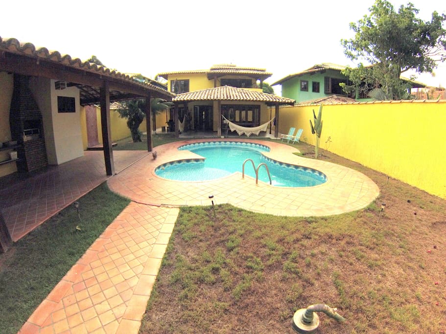 Vista da entrada da casa. Piscina à frente, churrasqueira e estacionamento à esquerda.