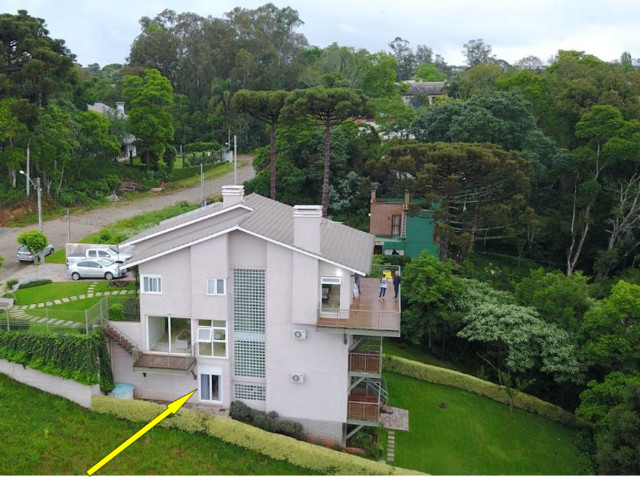 Foto aérea da residência. A seta indica a localização da suíte Alfazema na casa, com acesso direto ao bosque.