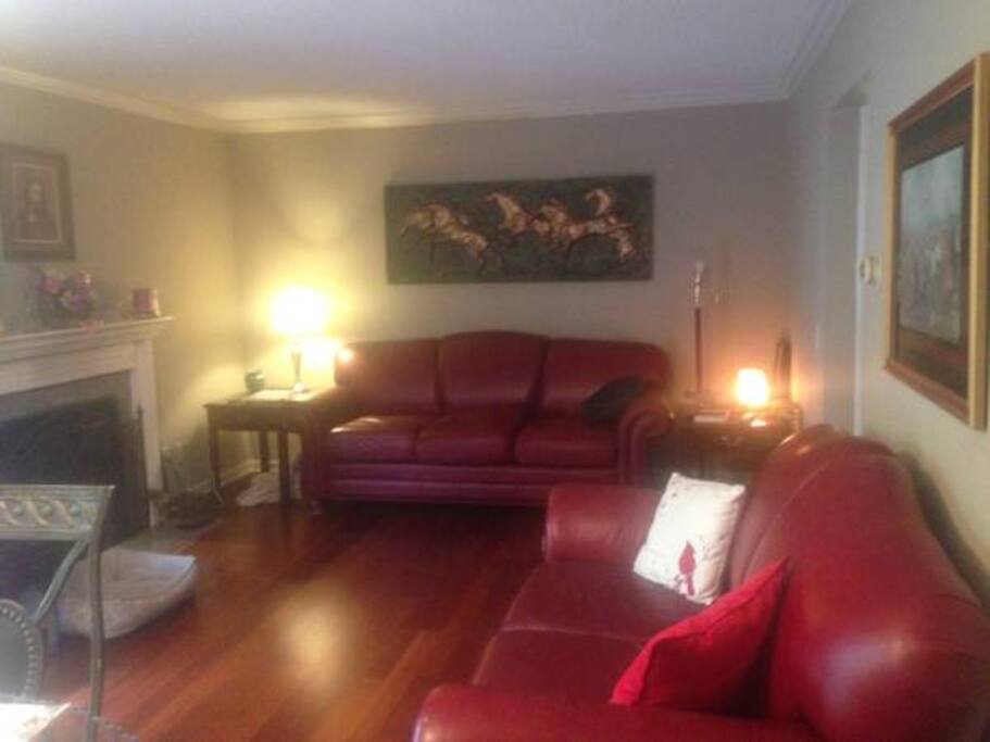 Living room with cherrywood floors, woodburning fireplace, crown molding and french doors leading to deck