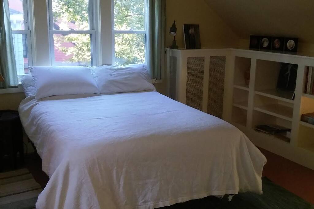 Double bed has lamps on both sides. Built in shelves stocked with art books.