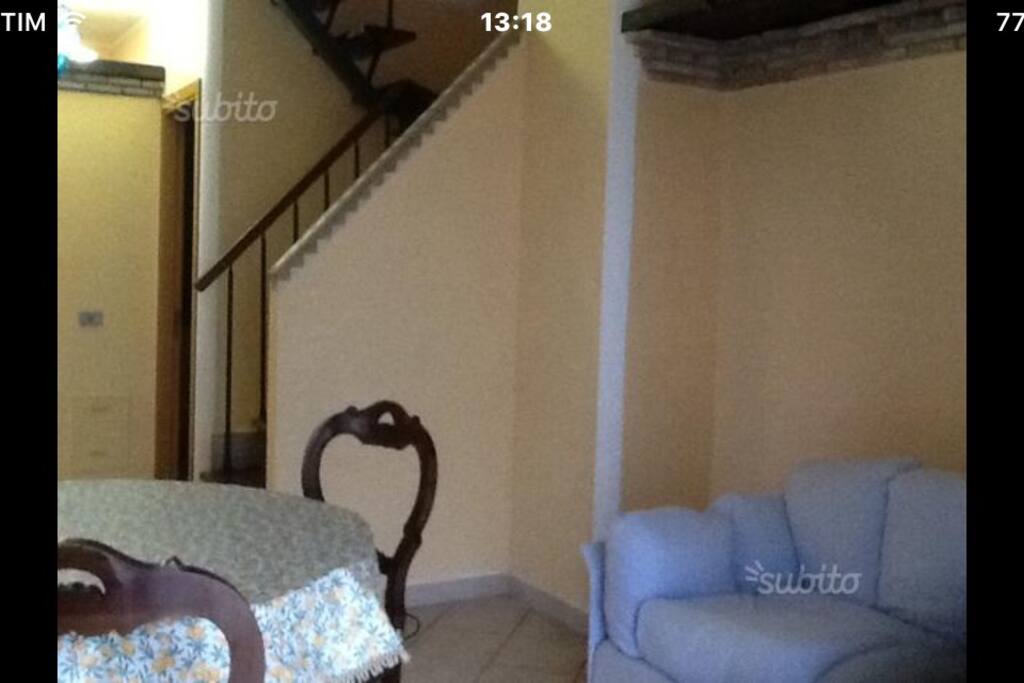 Soggiorno con scala in legno che conduce al piano di sopra