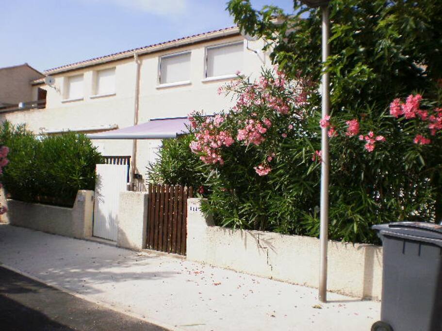 entrée de la maison avec terrasse, salon de jardin et store