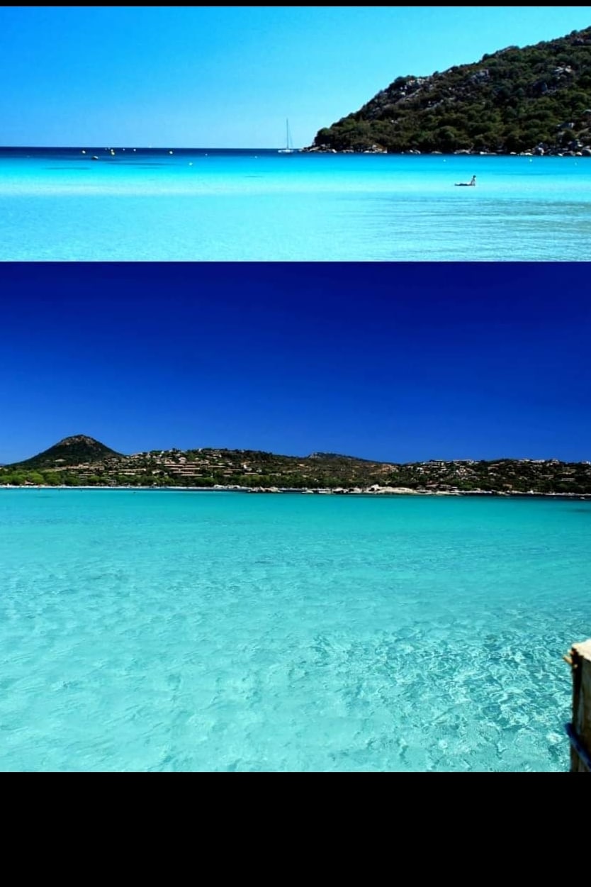 The image captures a serene coastal scene featuring clear blue waters gently lapping against the shore. Lush green hills rise in the background, providing a natural contrast against the vibrant sky. The tranquil atmosphere invites relaxation and appreciation of the surrounding nature.