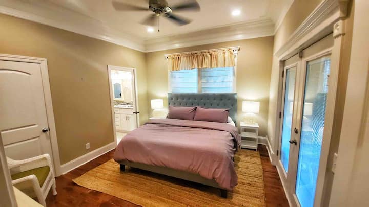 غرفة النوم الرئيسية في الطابق الرئيسي.  متصلة بالحمام الرئيسي وخزانة ملابس كبيرة وإمكانية الوصول المباشر إلى شرفة الفناء الخلفي.