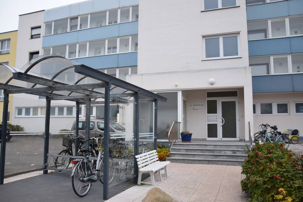 Hauseingang mit Fahraddabstellplatz und Autoparkplatz